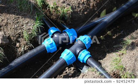 Connecting HDPE plastic water pipes in garden closeup 92452479