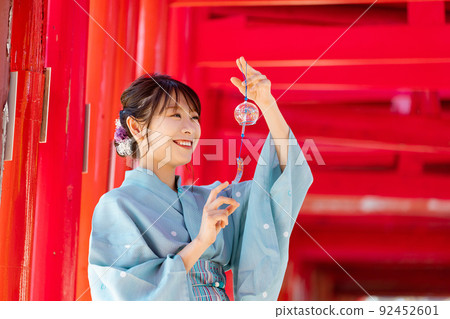 A woman in a yukata standing in a torii with a wind chime A woman in a yukata standing in a torii with a wind chime 92452601