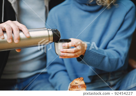 Cropped photo of a thermo cup in hands of couple 92454227