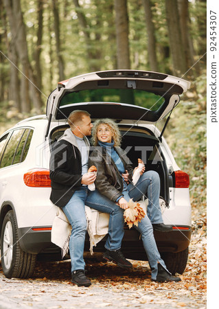 Romantic couple sitting in a trunk of white car in a forest and hugging 92454307