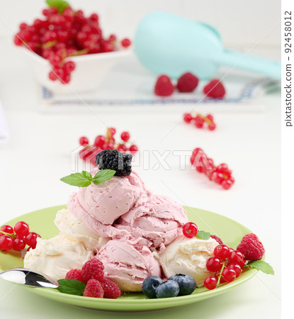 Vanilla and raspberry ice cream scoops on a round green plate Vanilla and raspberry ice cream scoops on a round green plate 92458012