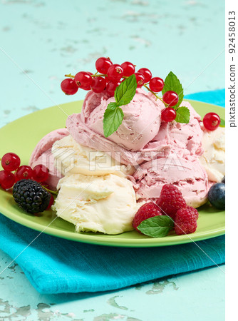 Vanilla and raspberry ice cream scoops on a round green plate 92458013