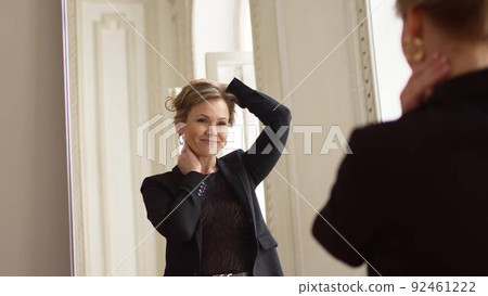 an attractive middle-aged woman looks at her reflection in the mirror. 92461222
