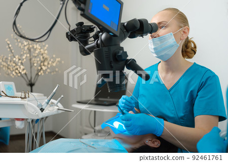 Female dentist using dental microscope Female dentist using dental microscope 92461761