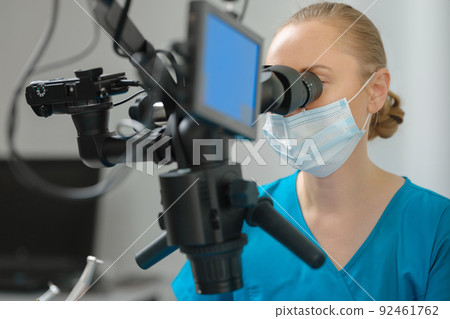 Female dentist using dental microscope Female dentist using dental microscope 92461762