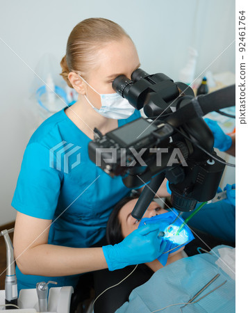 Female dentist using dental microscope Female dentist using dental microscope 92461764