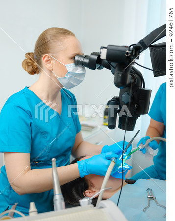 Female dentist using dental microscope Female dentist using dental microscope 92461765