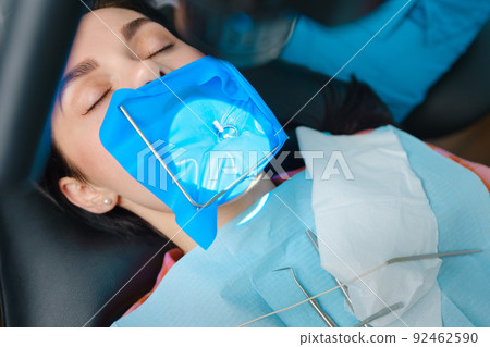 Closeup portrait of a female patient with a cofferdam system in a modern dental office. Dental equipment Closeup portrait of a female patient with a cofferdam system in a modern dental office. Dental equipment 92462590