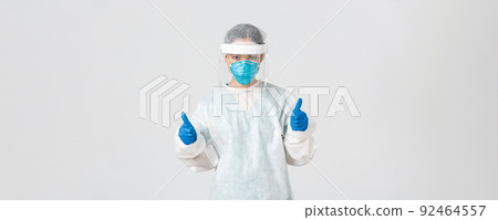 Covid-19, coronavirus disease, healthcare workers concept. Serious-looking confident young asian female doctor, infectionist in personal protective equipment showing thumbs-up, enter dangerious zone 92464557