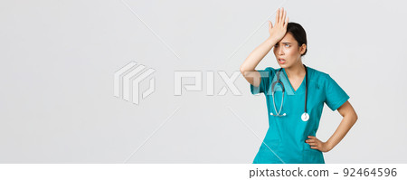 Covid-19, healthcare workers, pandemic concept. Annoyed and pissed-off asian female doctor in scrubs slap forehead, facepalm and eyeroll from someone stupid, tired standing white background 92464596