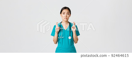 Covid-19, healthcare workers, pandemic concept. Hopeful nervous asian female intern in scrubs waiting for news, doctor cross fingers and biting lip as looking at camera, praying Covid-19, healthcare workers, pandemic concept. Hopeful nervous asian female intern in scrubs waiting for news, doctor cross fingers and biting lip as looking at camera, praying 92464615