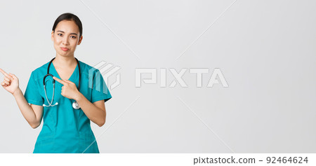 Covid-19, healthcare workers, pandemic concept. Skeptical and doubtful asian female nurse in scrubs pointing upper left corner and grimacing unamused, dont like product, being hesitant 92464624