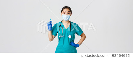 Covid-19, coronavirus disease, healthcare workers concept. Amused smiling asian physician, female doctor in medical mask and rubber gloves, prepared syringe with vaccine for shot, white background Covid-19, coronavirus disease, healthcare workers concept. Amused smiling asian physician, female doctor in medical mask and rubber gloves, prepared syringe with vaccine for shot, white background 92464655