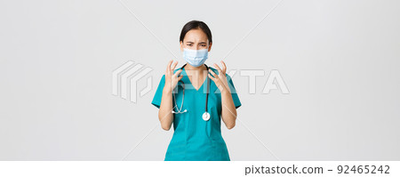 Covid-19, coronavirus disease, healthcare workers concept. Angry and pissed-off asian female doctor, physician in medical mask and scrubs, clench fists outraged, looking furious, white background Covid-19, coronavirus disease, healthcare workers concept. Angry and pissed-off asian female doctor, physician in medical mask and scrubs, clench fists outraged, looking furious, white background 92465242