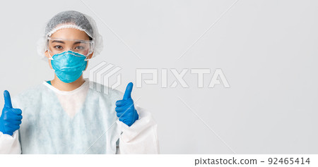 Covid-19, coronavirus disease, healthcare workers concept. Close-up of confident professional female asian doctor, tech lab employee in personal protective equipment show thumbs-up in approval 92465414