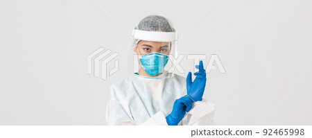 Covid-19, coronavirus disease, healthcare workers concept. Close-up of confident, professional female doctor put on personal protective equipment and rubber gloves to examine patient 92465998