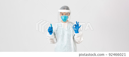 Covid-19, coronavirus disease, healthcare workers concept. Serious asian female doctor, professional researcher in personal protective equipment showing okay gesture, holding test-tube with vaccine 92466021