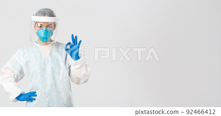 Covid-19, coronavirus disease, healthcare workers concept. Serious-looking professional female asian doctor in personal protective equipment, showing okay gesture, ensure safety of patient 92466412