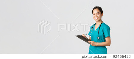 Healthcare workers, preventing virus, quarantine campaign concept. Smiling friendly female doctor, nurse in scrubs writing dorn results analysis at clipboard, standing white background 92466433