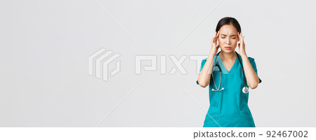 Covid-19, healthcare workers, pandemic concept. Overworked and tired young asian female nurse close eyes, grimacing from headache, feel dizzy, night shift with coronavirus patients, white background Covid-19, healthcare workers, pandemic concept. Overworked and tired young asian female nurse close eyes, grimacing from headache, feel dizzy, night shift with coronavirus patients, white background 92467002