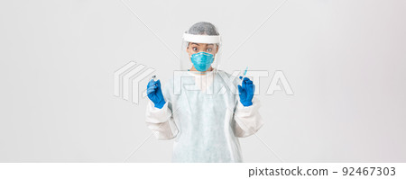 Covid-19, coronavirus disease, healthcare workers concept. Amazed and excited female asian doctor, infectionist in personal protective equipment, holding syringe and ampoule with vaccine Covid-19, coronavirus disease, healthcare workers concept. Amazed and excited female asian doctor, infectionist in personal protective equipment, holding syringe and ampoule with vaccine 92467303