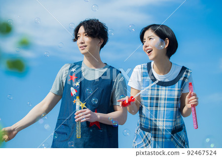 Nursery teacher men and women soap bubbles 92467524