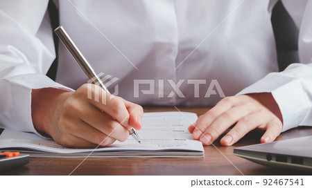 Hand of newly graduated female student filling out application documents. 92467541