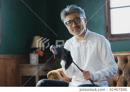 Gray-haired man polishing a golf club Gray-haired man polishing a golf club 92467898