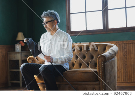 Gray-haired man polishing a golf club 92467903