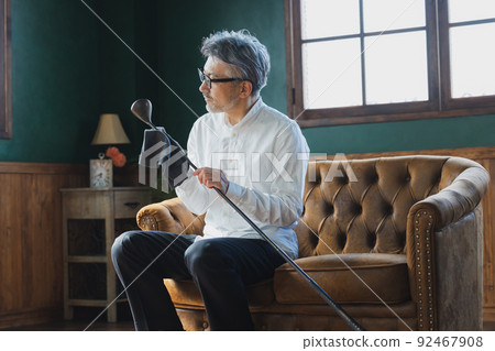 Gray-haired man polishing a golf club 92467908