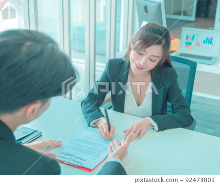 Business man is inviting Business woman to sign contract document agreement on the table. Business man is inviting Business woman to sign contract document agreement on the table. 92473001