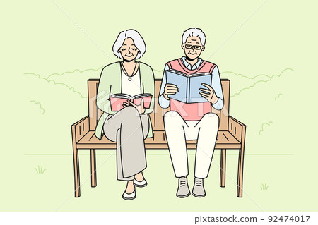 Mature couple on bench reading books Mature couple on bench reading books 92474017