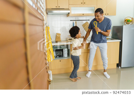 African American Father and his little boy dancing while cooking 92474033