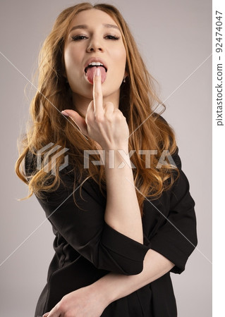 portrait of redhead business woman in black suit lick middle finger - fuck symbol portrait of redhead business woman in black suit lick middle finger - fuck symbol 92474047