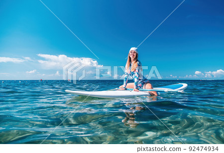 Woman sup sea. Happy healthy fit woman in bikini relaxing on a sup surfboard, floating on the clear turquoise sea water. Recreational Sports. Stand Up Paddle boarding. Summer fun, holidays travel. 92474934
