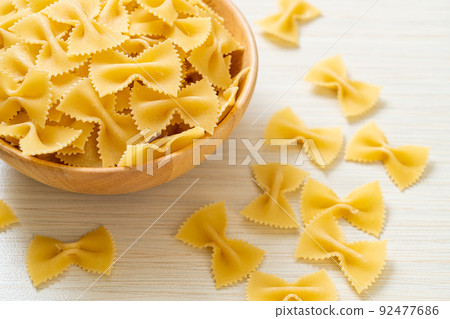 Dry uncooked farfalle pasta in bowl 92477686