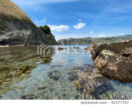Highly transparent sea, rocky shore and blue sky Highly transparent sea, rocky shore and blue sky 92477787