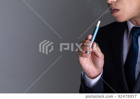 一個穿著西裝的男人抽著電子煙抽著 92478957