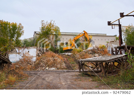 Yellow excavator breaks an old brick building. Yellow excavator breaks an old brick building. 92479062