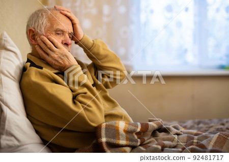 gray haired elderly man agonizing headache at home 92481717