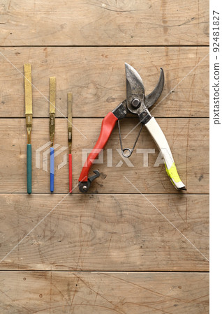 Pruning scissors and blade sharpening lined up on a board 92481827