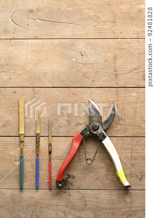 Pruning scissors and blade sharpening lined up on a board 92481828