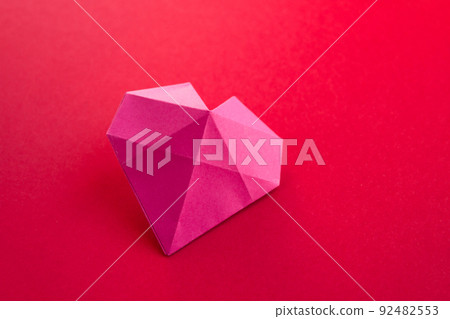 Pink paper heart origami isolated on a red background Pink paper heart origami isolated on a red background 92482553