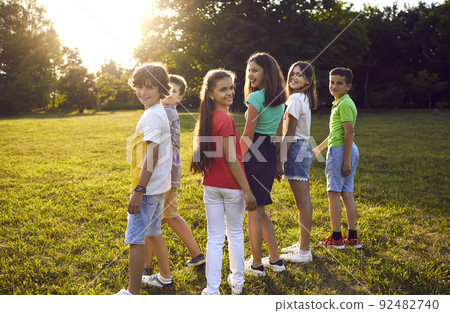 Happy teenagers girls and boys spending time together walking in sunny park holding hands Happy teenagers girls and boys spending time together walking in sunny park holding hands 92482740