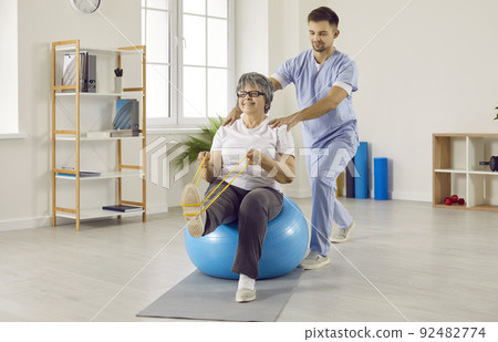 Professional male physiotherapist works with senior female patient in rehabilitation center. 92482774