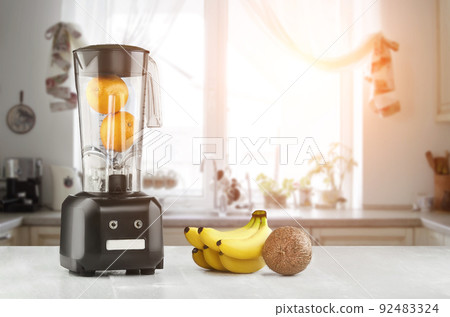 Metal food blender close-up with fresh exotic tropic fruits next to it on kitchen background with empty space. Sun flare Metal food blender close-up with fresh exotic tropic fruits next to it on kitchen background with empty space. Sun flare 92483324