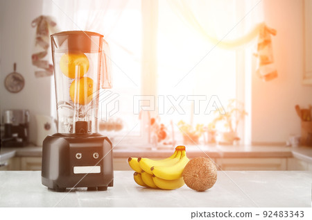 Metal food blender close-up with fresh exotic tropic fruits next to it on kitchen background with empty space. Sun flare Metal food blender close-up with fresh exotic tropic fruits next to it on kitchen background with empty space. Sun flare 92483343