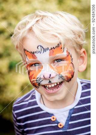 Cute happy little boy with his face painted Cute happy little boy with his face painted 92484306