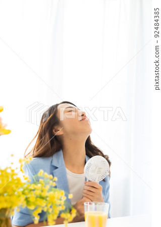 一個用電風扇尋求涼爽的女人 92484385