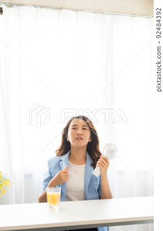 一個用電風扇尋求涼爽的女人 92484392